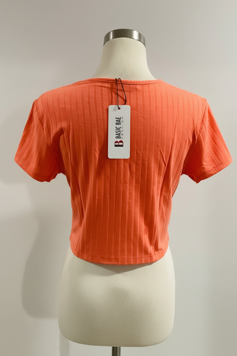 Orange t-shirt on a mannequin with a 'Basic Bae' tag against a plain background